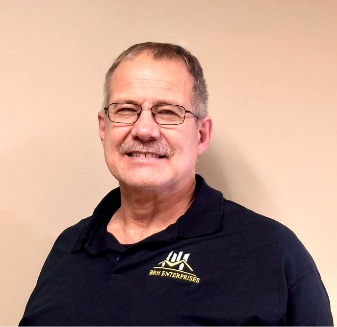 Smiling middle-aged man with glasses wearing navy BRM Enterprises polo shirt