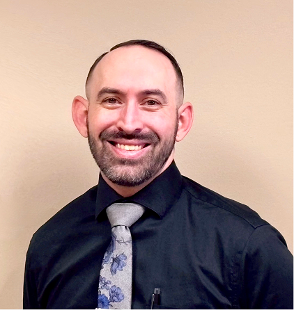 Smiling professional man in dark suit with floral tie against beige background