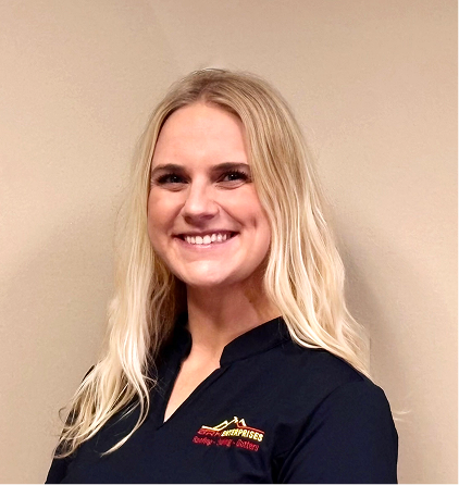 Smiling blonde woman in dark polo shirt with red logo against neutral background