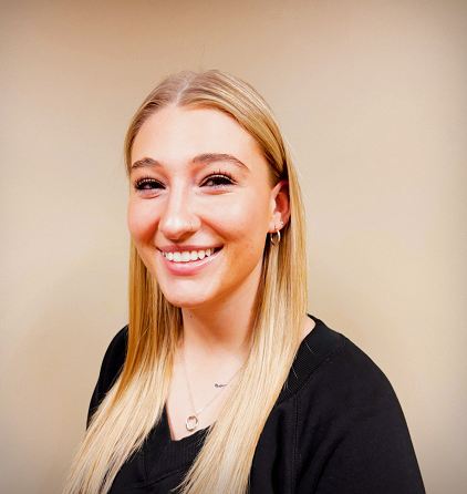 Smiling woman with long blonde hair against a beige background