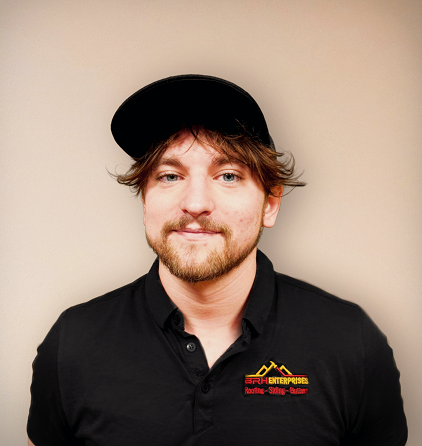 Smiling man wearing a black hat and shirt against beige background.