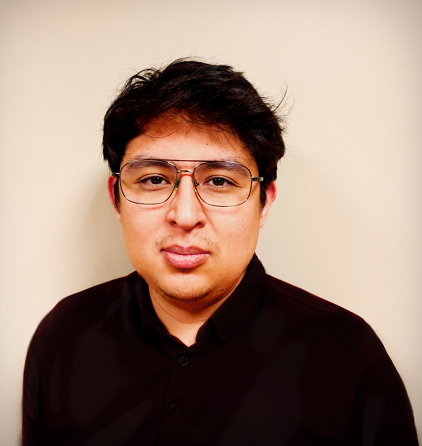 Portrait of a person with glasses wearing a dark shirt against a neutral background