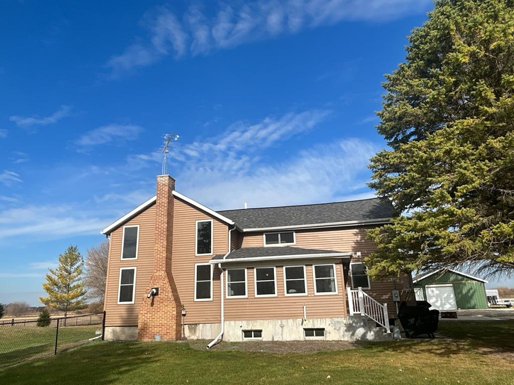 Rural two-story house with brick chimney under clear blue sky