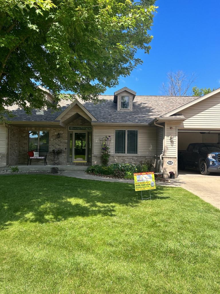 Charming suburban home with manicured lawn and sign in driveway